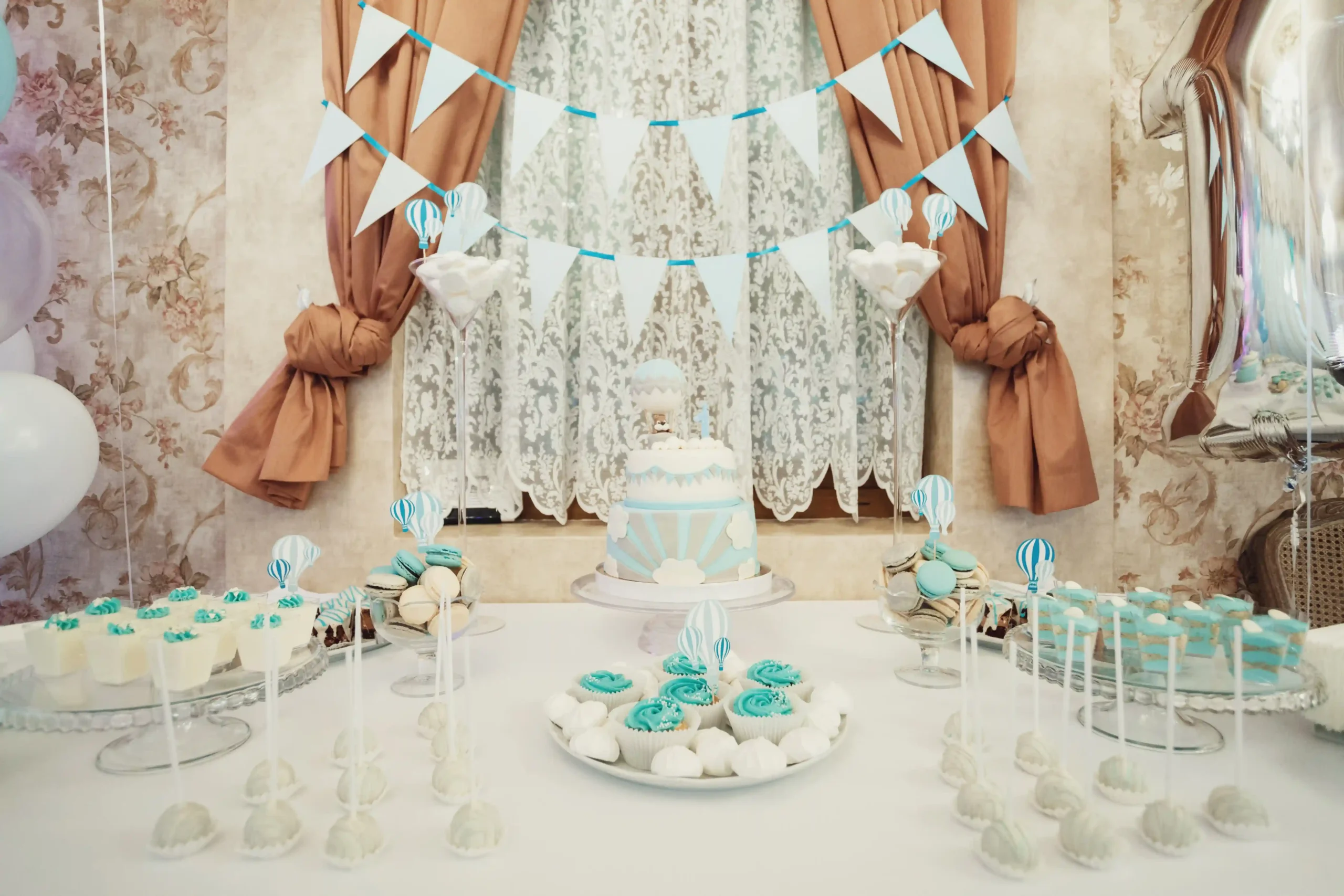 White and light blue birthday party decoration in Dubai with cake table setup and themed balloon backdrop.